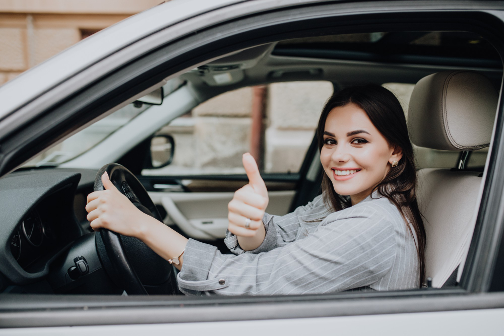 beautiful young latin woman driving her brand new car showing her thumb up